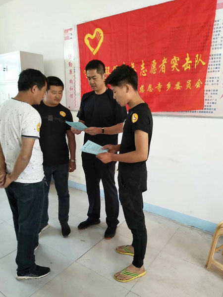 齊剛(右二)正帶領著村青年志愿者突擊隊一起研究改善村容村貌的措施