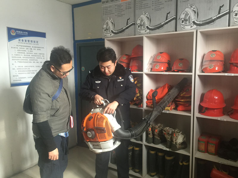 民警王雍賀向記者（左）講解新進的輕便型德國進口風(fēng)力滅火器的使用
