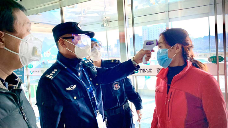王鵬（左二）對(duì)旅客進(jìn)行體溫檢測(cè)