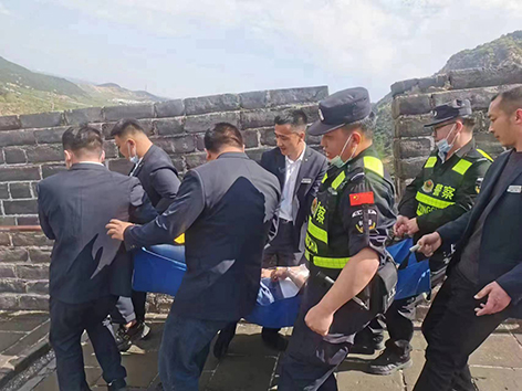 民警與景區(qū)工作人員將患病游客抬下長城。