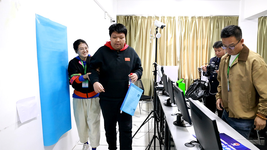 遼寧開放大學(xué)考區(qū)考務(wù)人員幫助盲人考生參加考試。