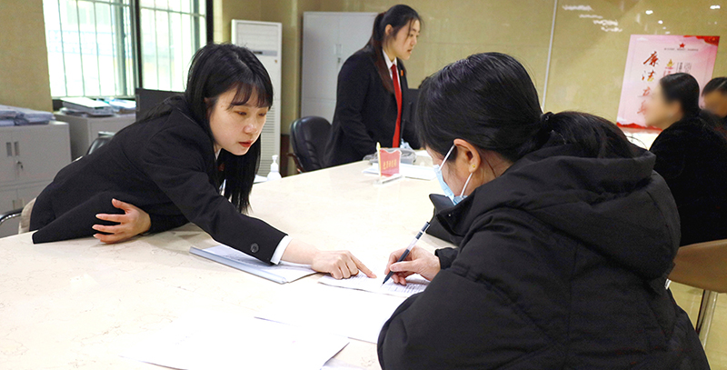 訴訟服務(wù)中心窗口工作人員正在指導(dǎo)前來(lái)立案的王女士填寫(xiě)要素式起訴狀